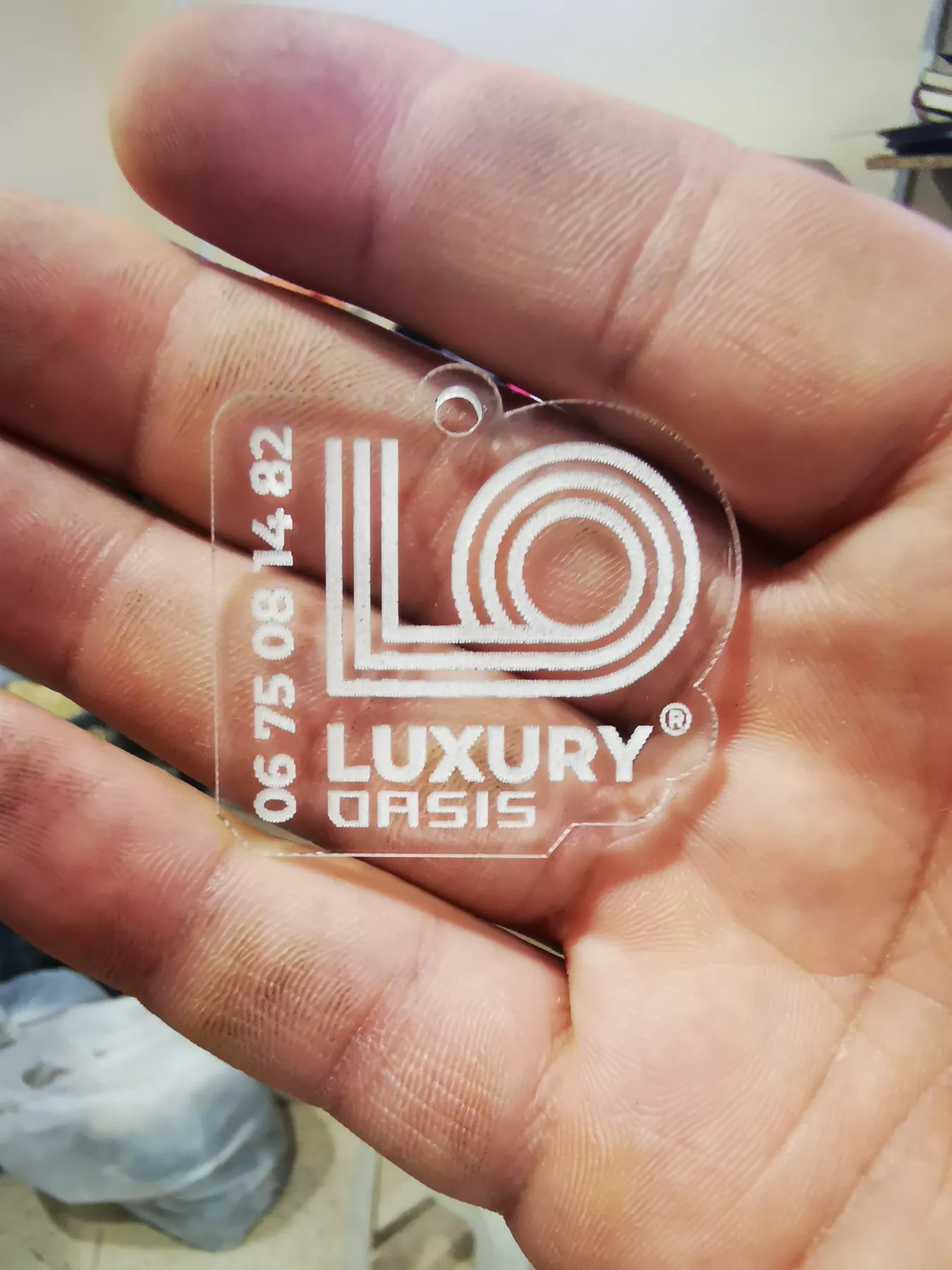 Porte-clés en plexiglas gravé Luxury Oasis tenu en main